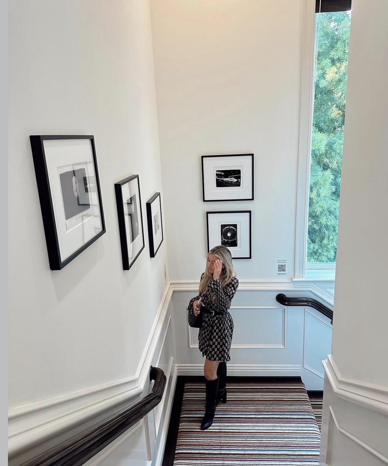 Paloma considering framed prints on a collected stairwell wall